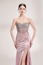 A woman stands against a light background, wearing a pink satin gown with a beaded, sheer bodice. It has thin straps, a ruched skirt, and a high side slit. The contrast of the sparkling beads and smooth satin fabric exudes elegance, perfect for formal galas or evening events, radiating charm.3
