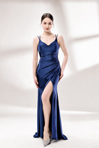 Set against a light background, a woman wears a navy - blue satin gown. It boasts thin straps, a draped neckline, and a mermaid silhouette with a high side slit. The smooth fabric and ruched design exude sophistication, ideal for formal events like proms.1