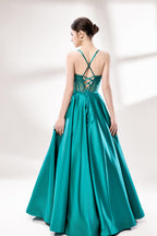 A woman stands against a light background, wearing a teal satin gown. It has thin straps, a sweetheart neckline, and a voluminous skirt. The bodice features sheer fabric with bead embellishments, combining elegance and romance. Perfect for formal events like weddings, it exudes charm.2