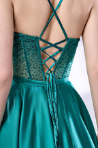 A woman stands against a light background, wearing a teal satin gown. It has thin straps, a sweetheart neckline, and a voluminous skirt. The bodice features sheer fabric with bead embellishments, combining elegance and romance. Perfect for formal events like weddings, it exudes charm.5