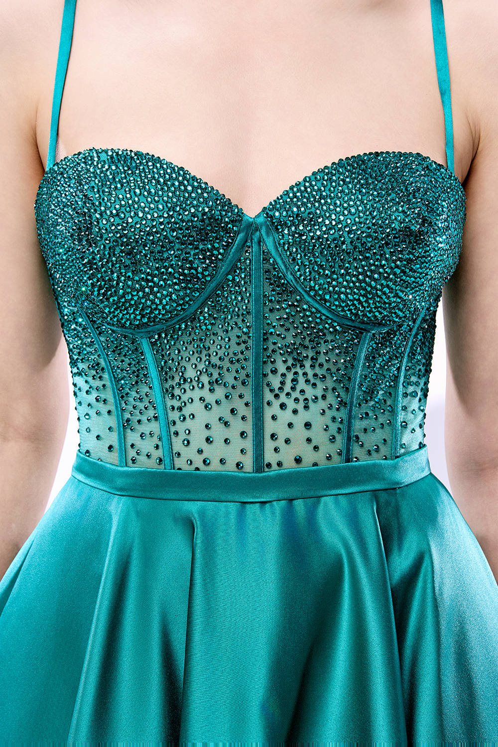 A woman stands against a light background, wearing a teal satin gown. It has thin straps, a sweetheart neckline, and a voluminous skirt. The bodice features sheer fabric with bead embellishments, combining elegance and romance. Perfect for formal events like weddings, it exudes charm.6