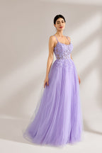 Set against a light backdrop, a woman wears a lavender tulle gown. It has thin straps, a sweetheart neckline with intricate lace embroidery on the bodice, and a flowing tulle skirt. The graceful design gives off a romantic and ethereal vibe, ideal for formal occasions such as proms or weddings.4