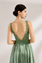 A woman with an elegant updo and a poised stance wears a sage - green satin gown. It has thin straps, a lace - detailed, V - neck bodice, and a high side slit. Paired with silver - tone heels, the outfit radiates grace, perfect for formal events like galas or weddings.6
