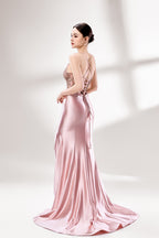 Set against a light backdrop, a woman dons a pink satin gown with a beaded, sheer bodice and a mermaid silhouette. The intricate bead patterns and flowing train add romance, combining sophistication and allure. Ideal for weddings or formal ceremonies, it exudes a regal aura.2