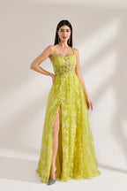 Bathed in soft light, a woman dazzles in a yellow floral - patterned gown. It has thin straps, a fitted bodice, and a high side slit. The flowing skirt creates an elegant and vibrant look, perfect for formal events or special occasions.3