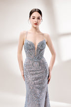 A woman stands against a light - hued background, wearing a light - grey, sheer gown adorned with intricate silver - toned bead patterns. It has thin straps, a deep V - neckline, and a mermaid silhouette. The detailed beadwork and sheer fabric create a glamorous look, perfect for proms or formal parties, radiating sophistication.5