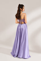 A woman with long, wavy dark hair and a confident pose wears a light - purple satin gown. It has thin straps, a sheer lace - detailed bodice, and a high side slit. Paired with silver - tone heels, the outfit radiates elegance, perfect for formal events like galas or evening receptions.2