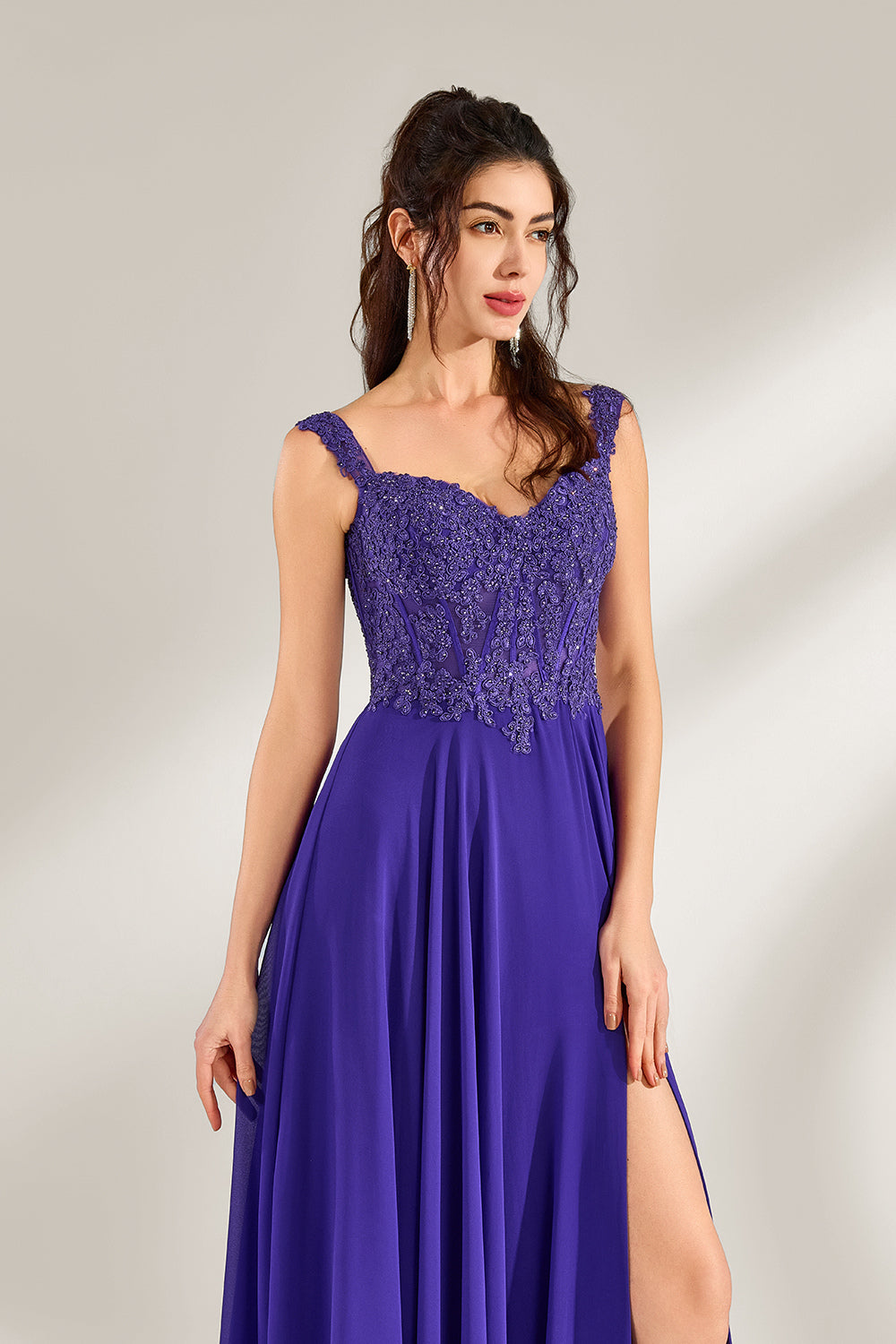 Against a light backdrop, a woman is seen in a purple chiffon gown. It comes with wide straps, a sweetheart neckline, and the bodice is decorated with intricate lace embroidery. There's also a high side slit, and the flowing chiffon skirt gives an elegant and graceful appearance, ideal for formal events such as proms or weddings.6