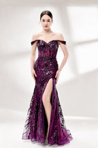 Set against a light background, a woman wears a purple tulle gown embellished with sequin embroidery. It has thin straps, a sweetheart neckline, a sheer bodice patterned with florals, and a mermaid skirt with a high side slit. Silver heels complete the look, with the sparkling sequins and refined silhouette ideal for proms or formal dinners.5