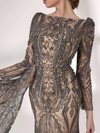 Under subtle lighting, a woman exudes elegance in a long - sleeved evening gown. The gown features a bateau neckline, intricate beadwork and lace patterns, creating a sheer - effect that's both sophisticated and alluring. Ideal for high - end formal occasions, it seamlessly combines luxury and grace.2