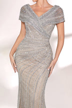 A woman stands against a light background, wearing a silver - grey beaded gown. It features off - shoulder sleeves, a V - neckline, and a mermaid silhouette. The intricate bead patterns and sheer fabric exude elegance, perfect for formal galas or weddings, radiating timeless charm.6