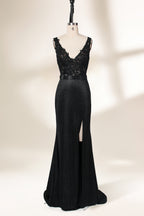 A photograph of a black, floor-length evening gown with a deep V-neck and lace detailing, featuring a thigh-high slit on the left side. The dress is displayed on a white mannequin with a black stand against a soft, beige background with diffused lighting creating gentle shadows. The gown exudes elegance and sophistication.32645.1