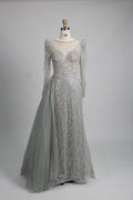 Silver long-sleeve mermaid gown with beaded lace texture and draped side overskirt