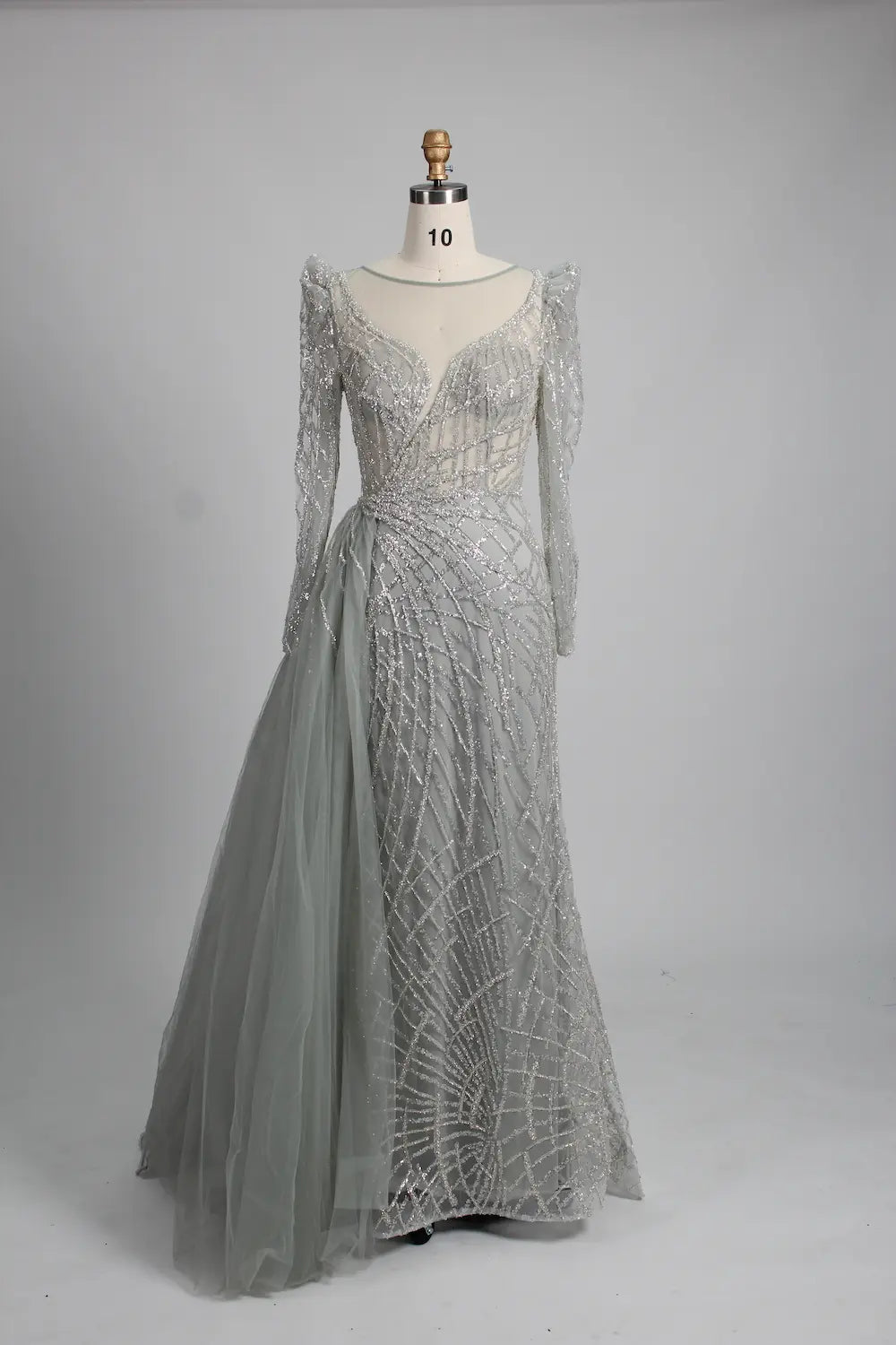 Silver long-sleeve mermaid gown with beaded lace texture and draped side overskirt