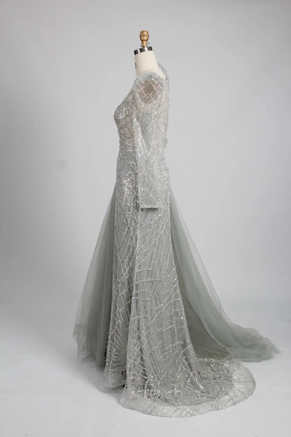 Silver long-sleeve mermaid gown, side view with tulle drape overskirt and beaded pattern