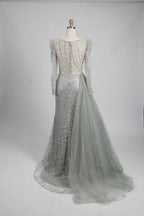 Silver long-sleeve mermaid gown with straight bateau neckline and flowing side tulle overskirt