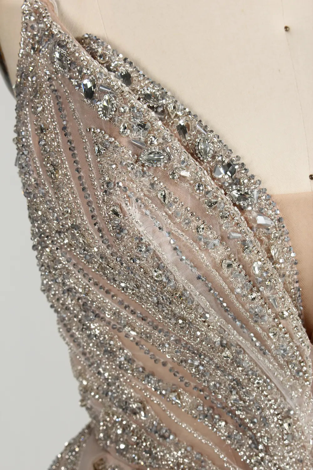 Close-up of champagne tulle with dense silver beaded embellishment and sequined lines