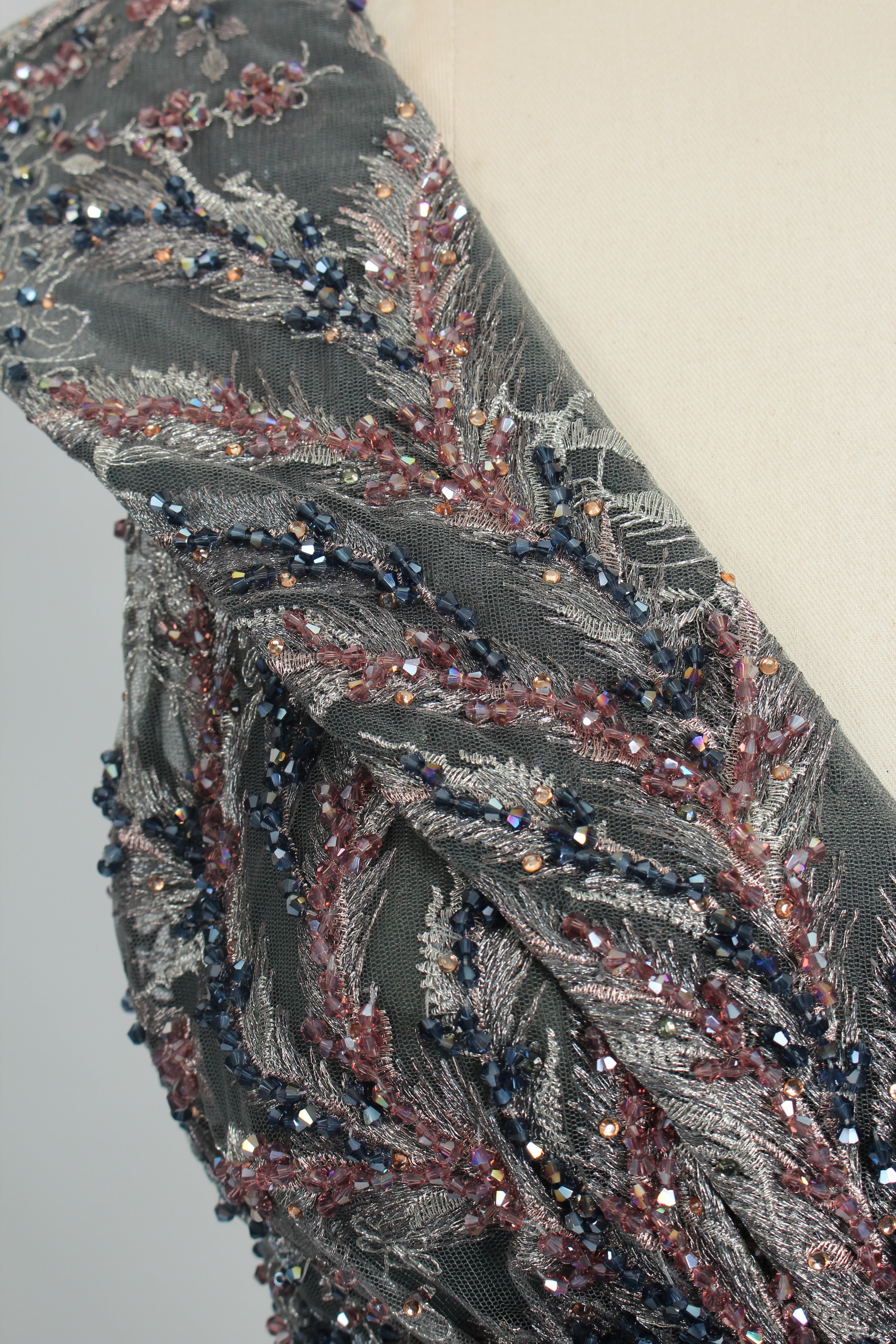 Close-up of dark gray beaded fabric on sleeveless V-neck evening dress bodice