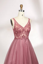 Photograph of a mannequin showcasing a floor-length, sleeveless, pink tulle gown with intricate lace detailing on the bodice and neckline. The gown features a fitted waist and flares out into a voluminous skirt, creating a ballerina-style silhouette. The mannequin stands against a plain white background with soft, diffused lighting casting subtle shadows.04
