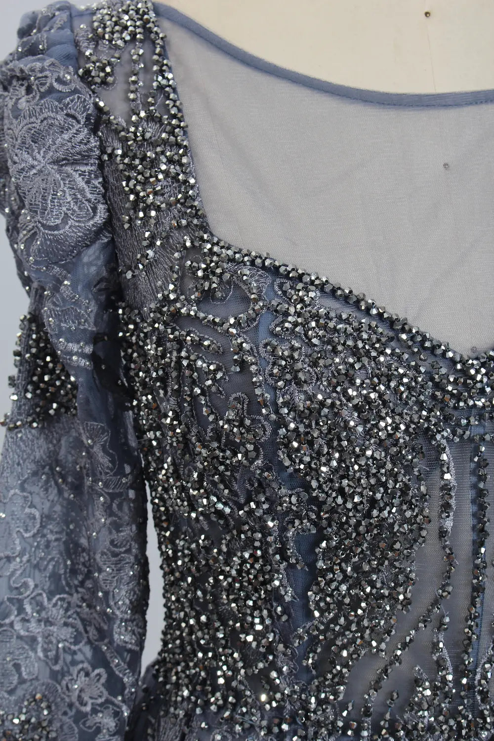 Close-up of dark blue beaded crystal filigree illusion neckline and sleeves