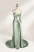 A mannequin showcases a strapless light - green satin gown against a soft, neutral backdrop. The dress features a twisted, criss - cross bodice with a subtle sheer panel and a mermaid silhouette, complete with a high side slit and a flowing train. The smooth, lustrous satin fabric and elegant design exude sophistication, perfect for formal galas or black - tie events.1
