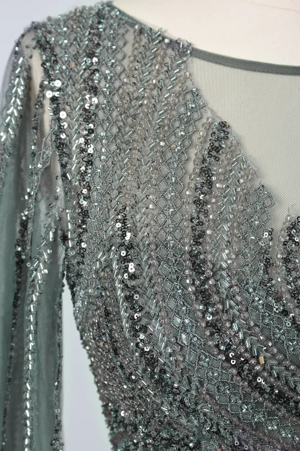 Close-up of beaded bodice and sheer cape sleeves with dense shimmering dark metallic sequins