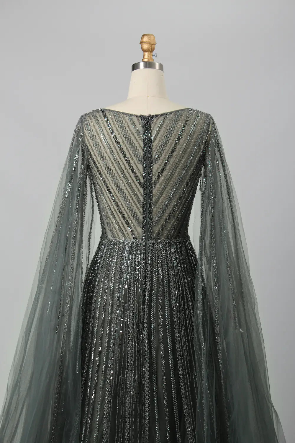 Back view of beaded A-line gown with V back and sheer cape sleeves, dark metallic beadwork