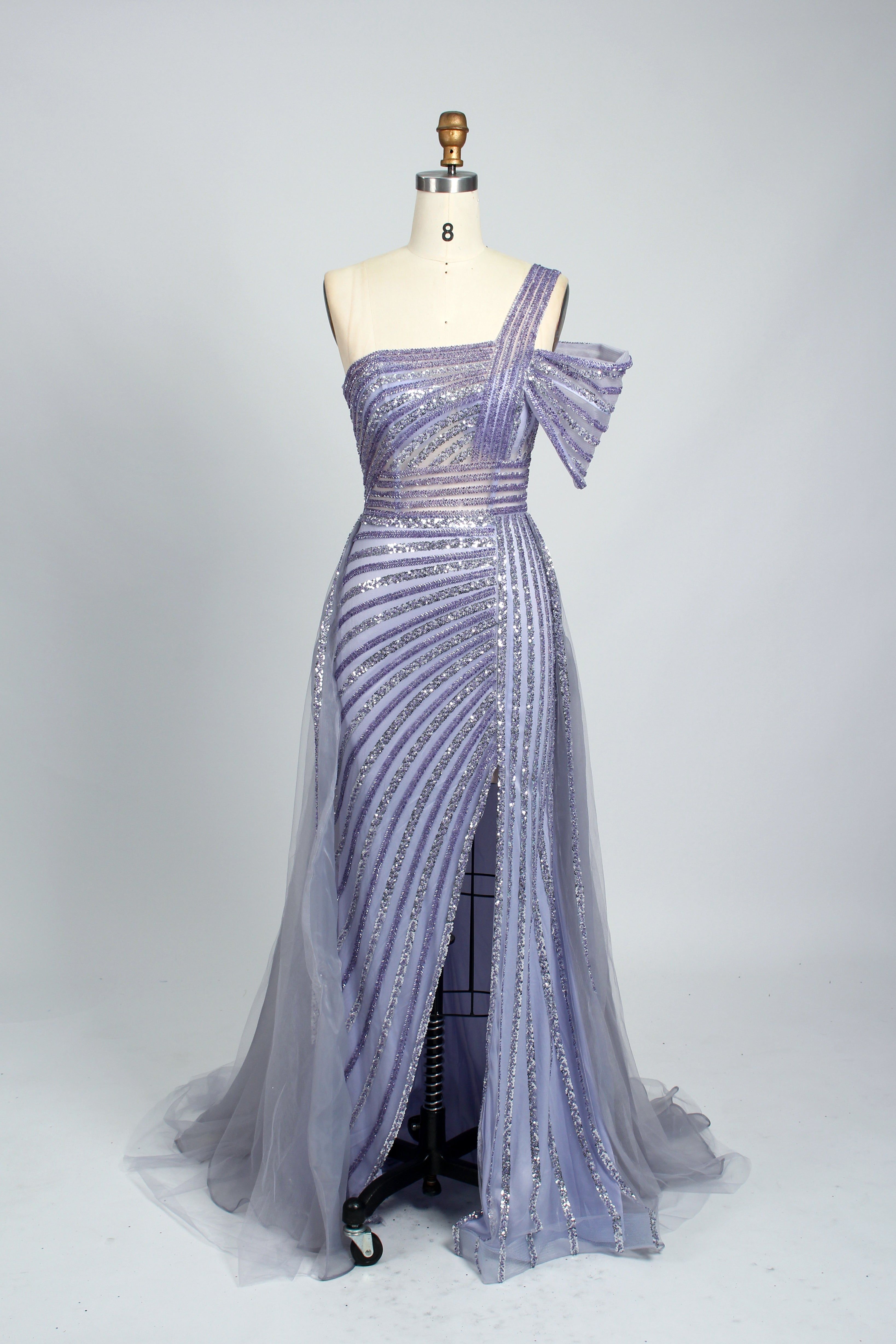 Against a light - hued backdrop, a woman dons a teal sequin gown with an one - shoulder design. It features a bow - detailed strap, a sheer waist panel, and a high side slit. The sparkling sequins and unique silhouette radiate glamour, perfect for formal dinners or galas.10