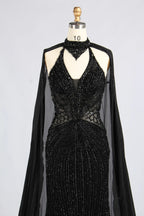 Black beaded halter gown with sheer cape sleeves, V-neck, and corset-style waist