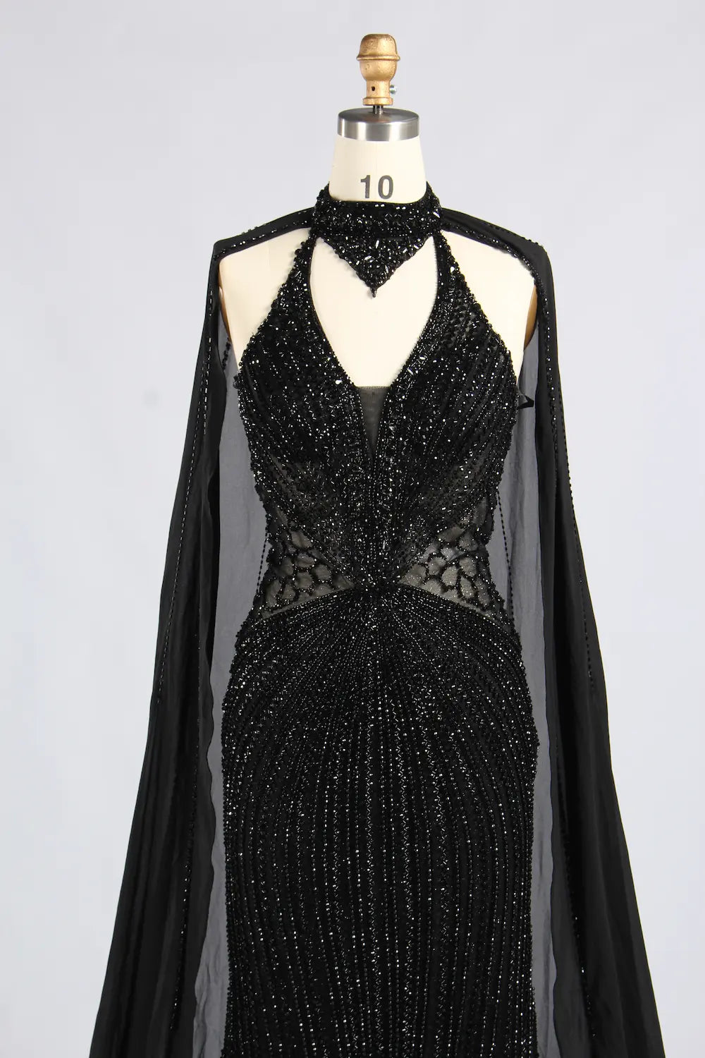 Black beaded halter gown with sheer cape sleeves, V-neck, and corset-style waist