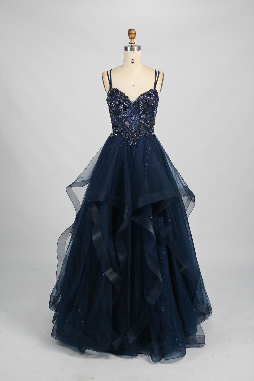 A mannequin displays a pink tulle gown. It features thin straps, a sweetheart neckline, intricate floral appliqués with sequins on the bodice, and a multi - layered, ruffled tulle skirt. The elegant design creates a romantic and glamorous look, perfect for formal events like proms or weddings.9