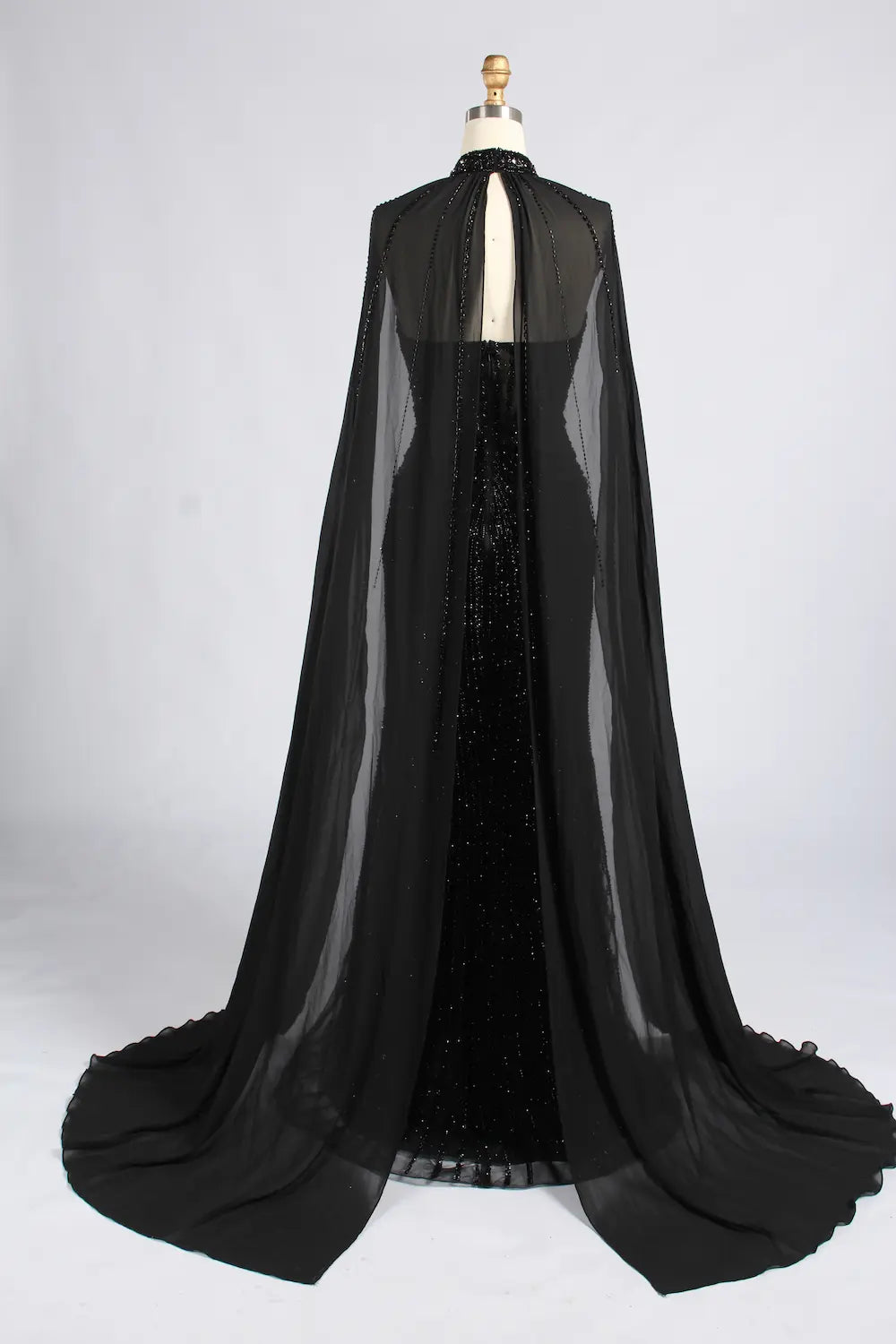 Back view of black beaded gown with sheer cape and long draped train