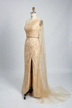 One-shoulder champagne sequin sheath gown with high side slit and long tulle overlay