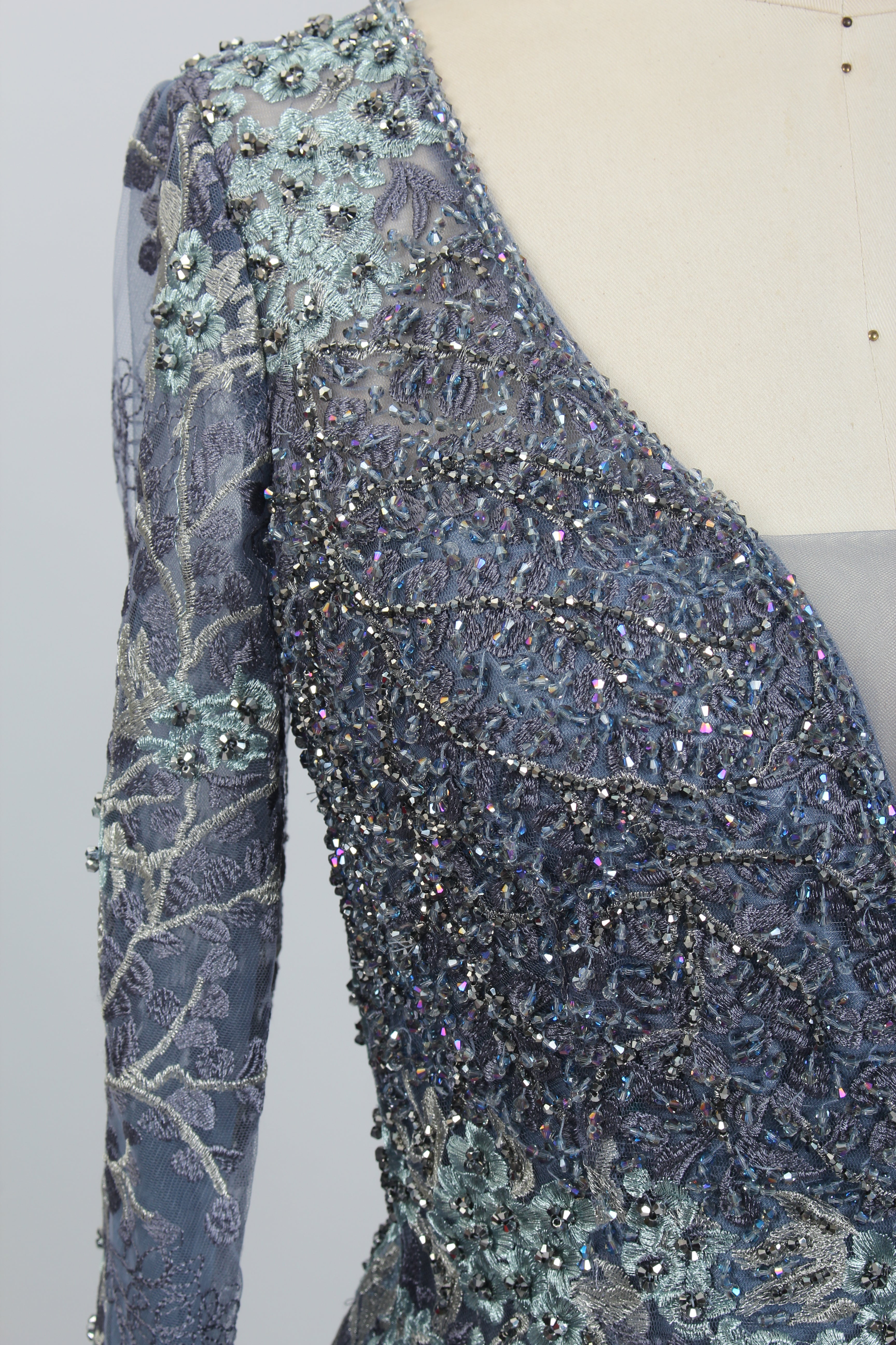 Light blue beaded tulle dress sleeve close-up with sparkling sequins and embroidery