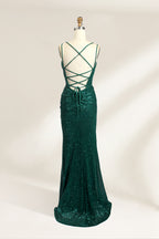 Photograph of a mannequin wearing a floor-length, deep green sequin dress with a plunging V-neckline, spaghetti straps, and a daring thigh-high slit on the left side. The dress has a fitted bodice and a flowing, slightly flared skirt. The mannequin is displayed against a plain white background with soft, diffused lighting creating gentle shadows.05