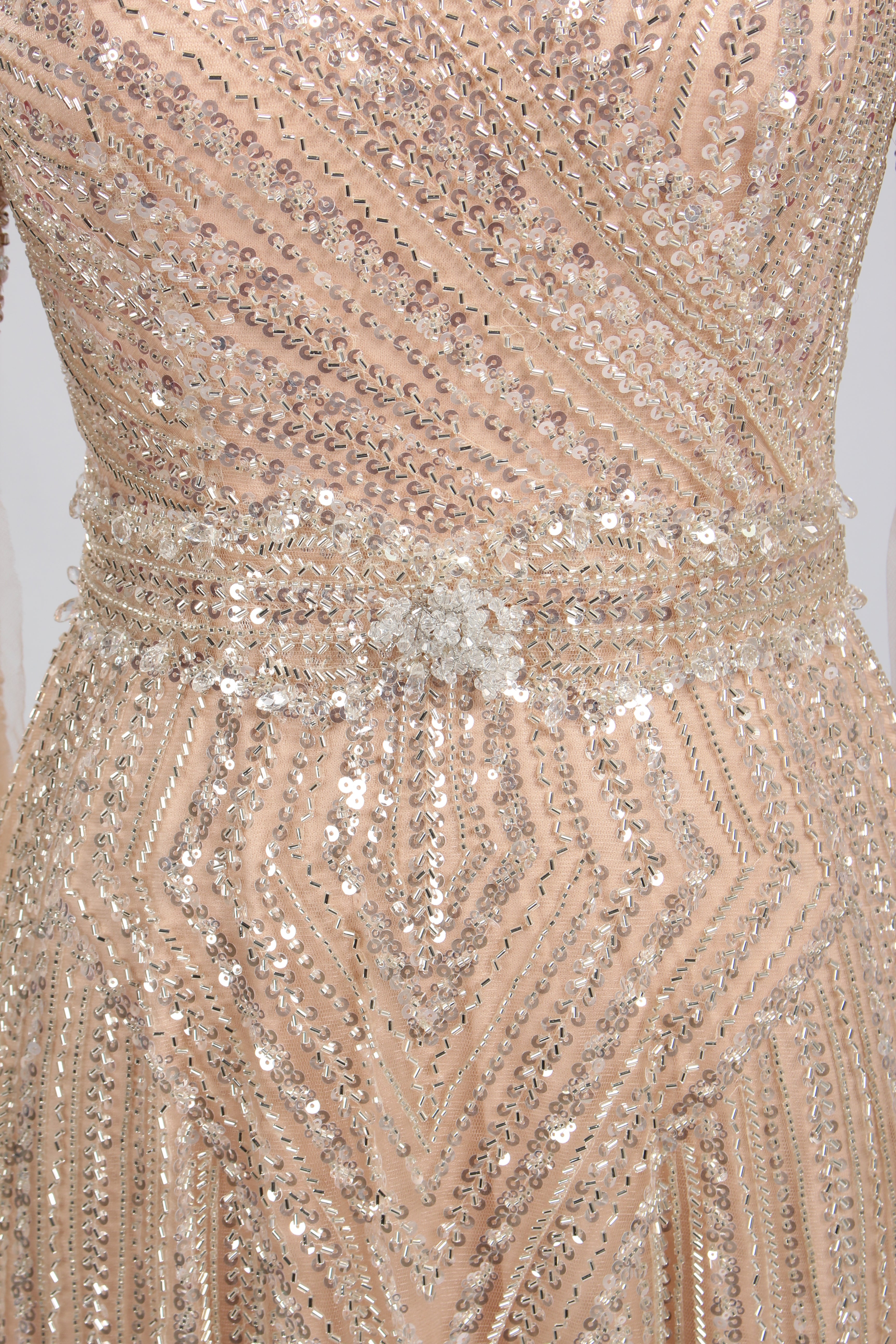 Close-up of champagne sequin V-neck bodice with draped beading and waist detail
